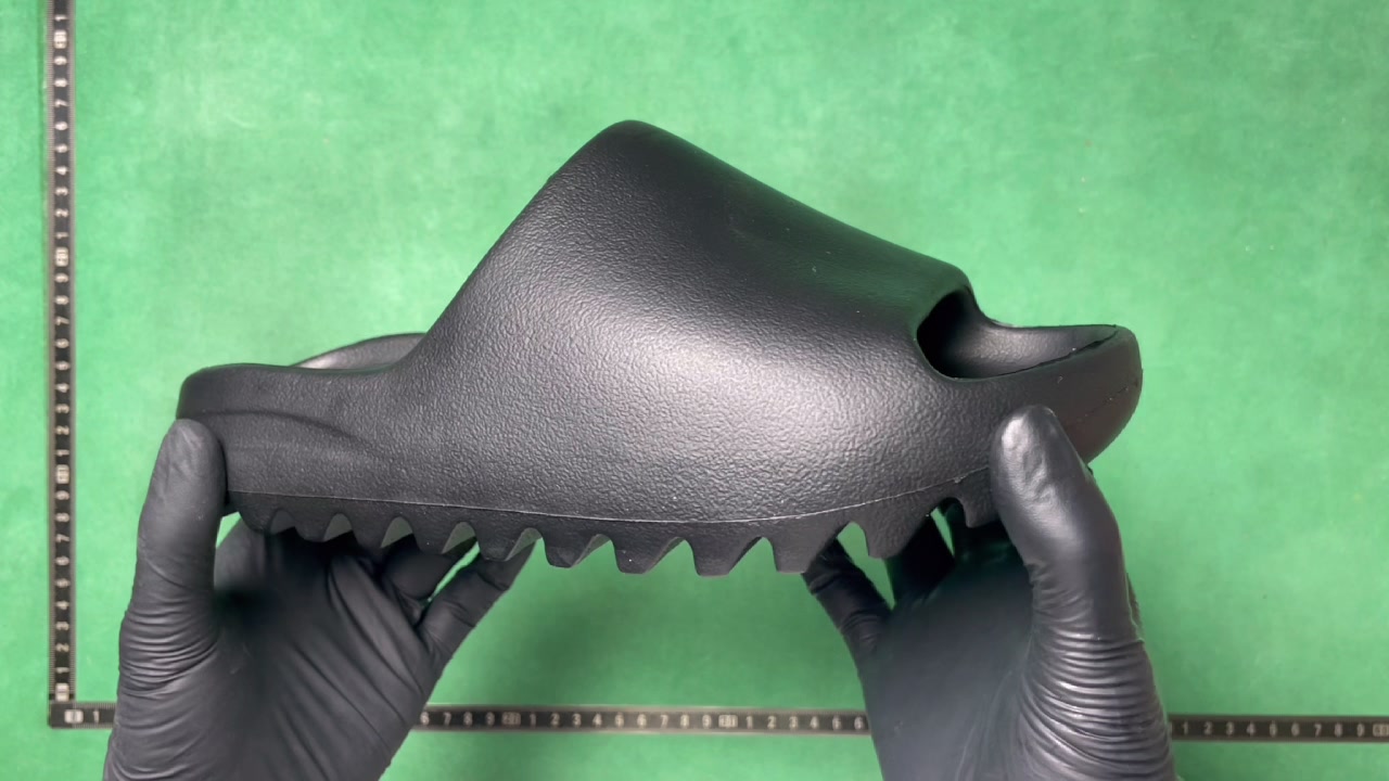 Black Adidas-marked sculpted foam slide shown from the side